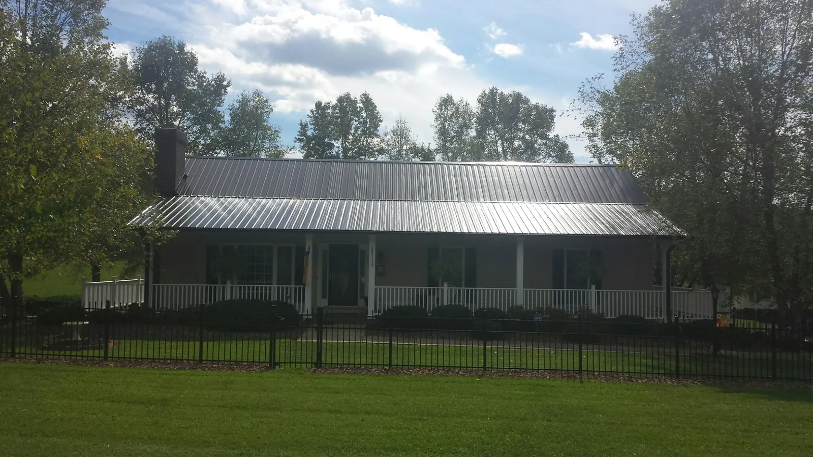 Gray metal roof on a brick ranch with a full width front porch — Gutter Guard Installation work by our crew in Kahoka