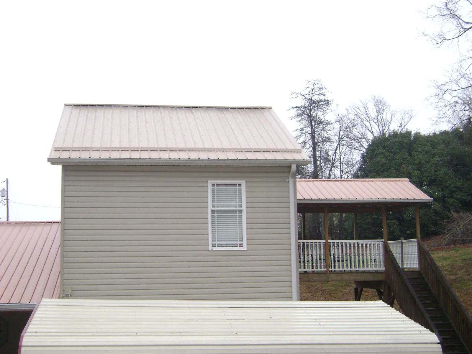 Tan metal roofs on a two story addition and attached porch, from a Roof Replacement job in Kahoka