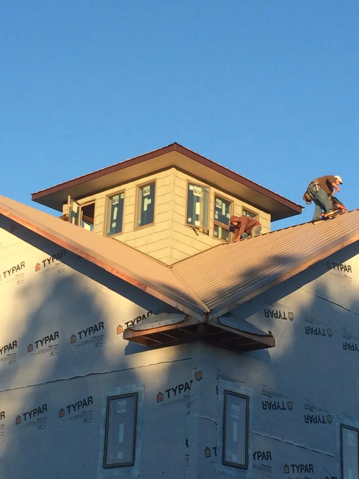 Roofers working around a rooftop cupola on a new metal roof at sunset — Roof Waterproofing in Kahoka by Roofing Brothers